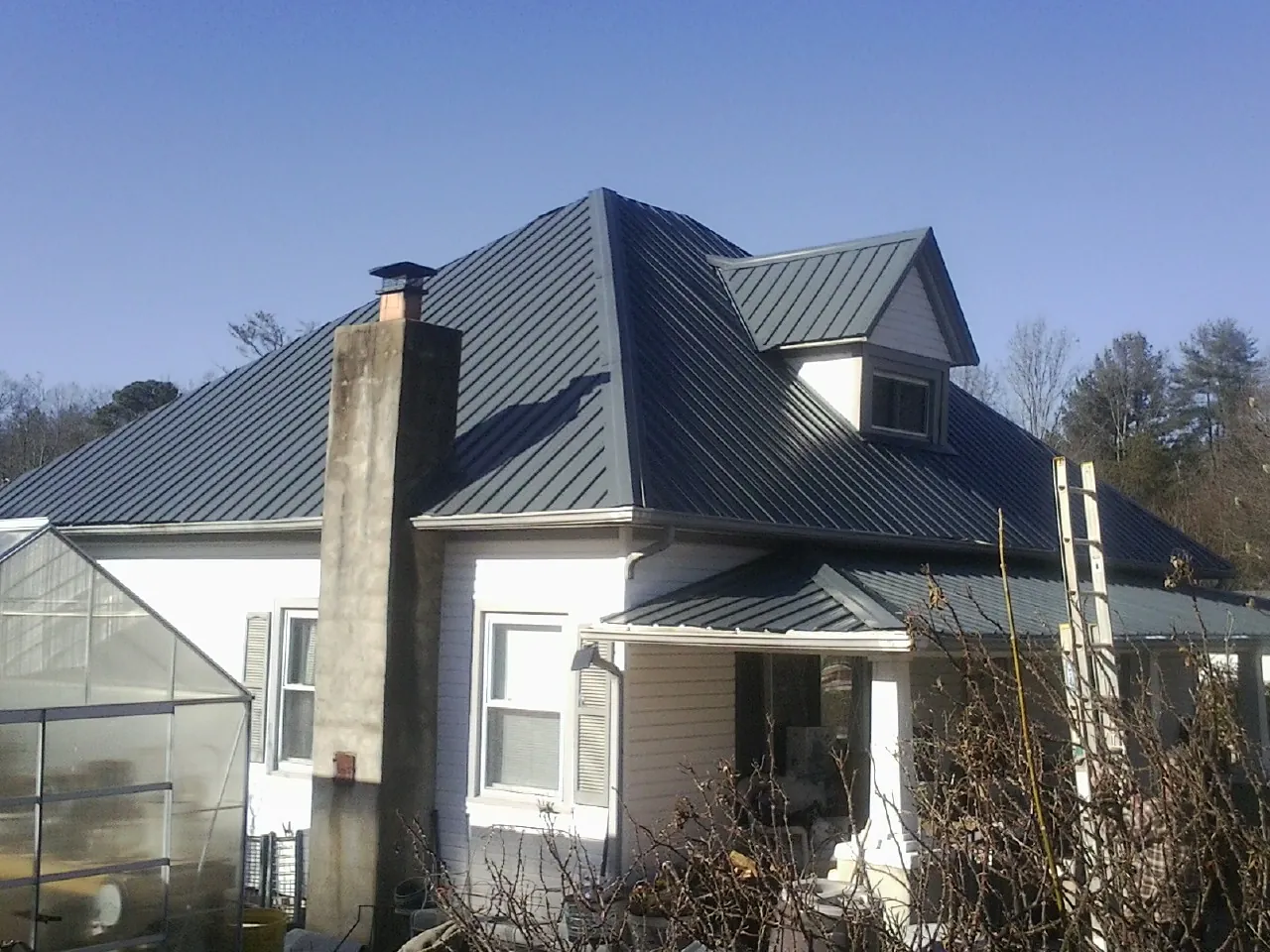 Dark blue standing seam metal roof on a white farmhouse with dormer — Slate & Tile Roof Repair by Roofing Brothers in Ocean Shores