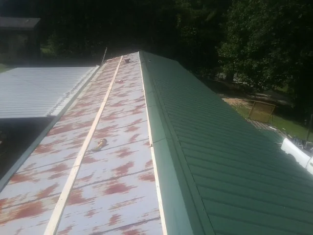 Old rusted panels beside newly installed green metal roofing — Wind Damage Roof Repair by Roofing Brothers in Ocean Shores