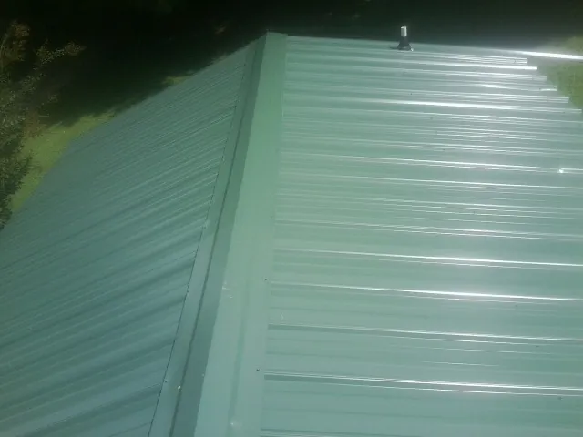 New green metal panels meeting at the ridge of a roof — Flat Roof Repair work by our crew in Ocean Shores