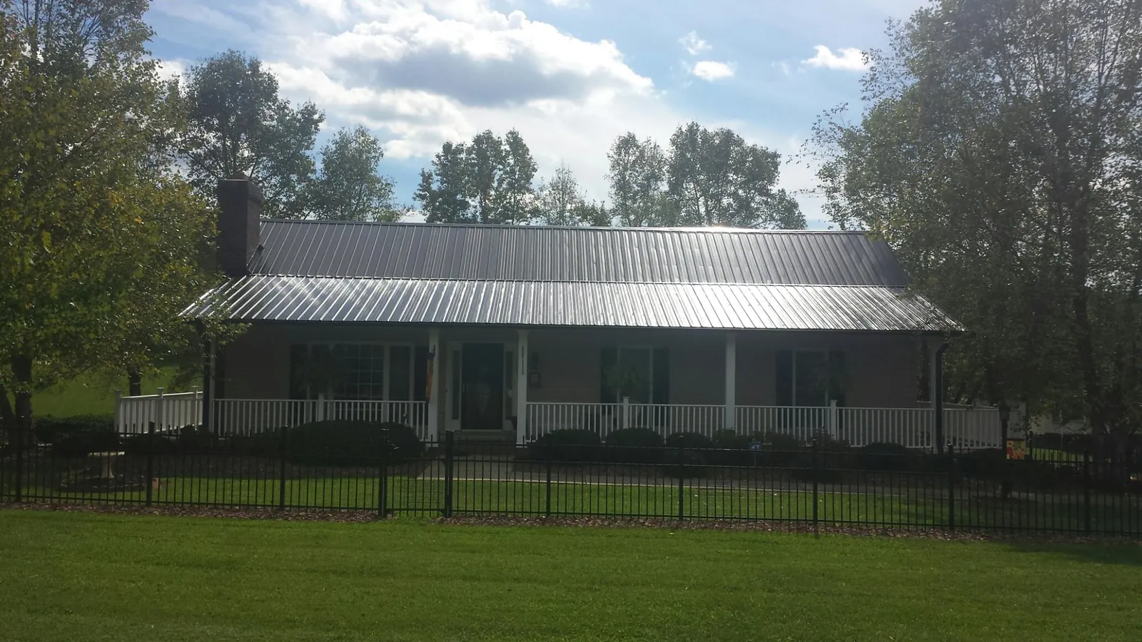 Gray metal roof on a brick ranch with a full width front porch — Gutter Guard Installation work by our crew in Ocean Shores