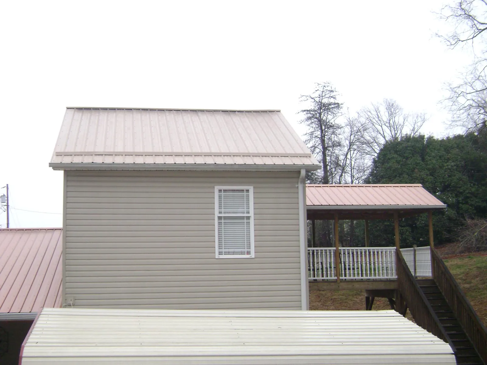 Tan metal roofs on a two story addition and attached porch, from a Roof Replacement job in Ocean Shores